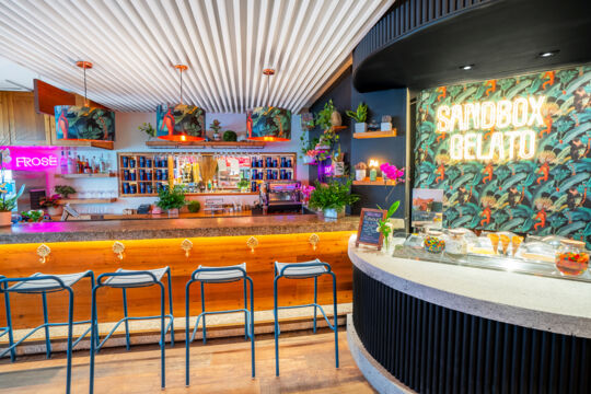 Bright and colorful indoor bar with neon signs and a gelato counter