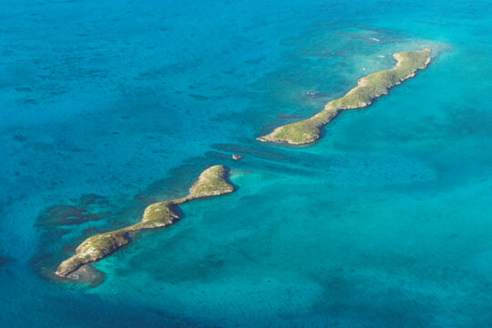 Aerial view of two long and narrow cays in turquoise ocean