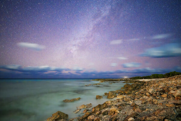Turks and Caicos night sky with Milky Way and constellations above a rocky beach.
