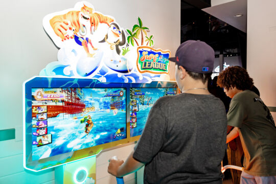 Kids playing a surfing game at an arcade. 