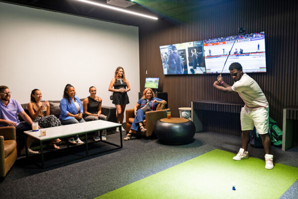 Group trying out a golf simulator at an interactive sports bar. 