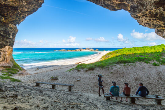 Beach with turquoise water and a rocky cay. 