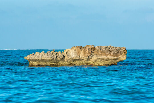 Small cay with low jagged cliffs in the ocean