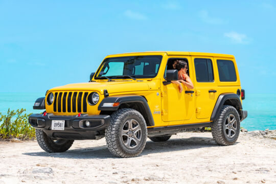 A yellow Jeep parked near the water in Turks and Caicos. 