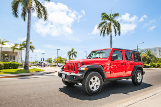 A red Jeep driving past Graceway Gourmet, Providenciales. 