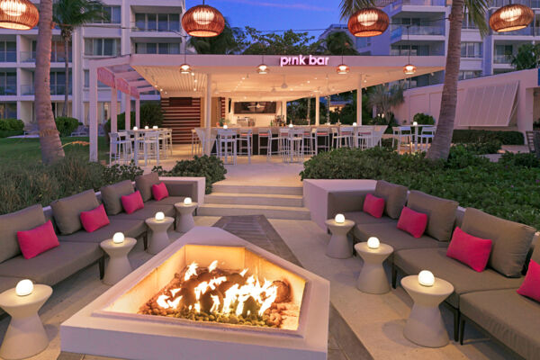 Beachfront bar with fire table at dusk.